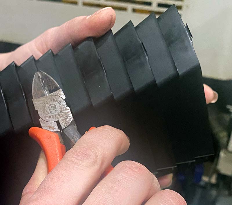 Hands holding pliers and plastic boxes